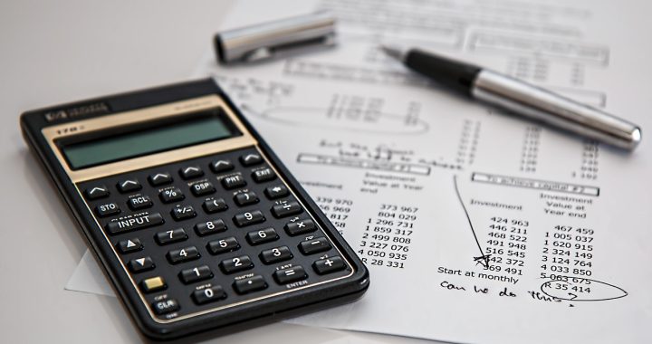 Calculatrice et documents fiscaux sur un bureau pour calculer la cotisation foncière des entreprises
