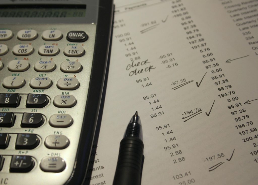 Mains calculant un budget de courses avec une calculatrice, un ticket de caisse et un carnet