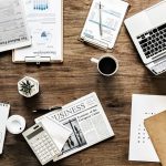 Calculatrice posée sur des relevés boursiers pour calculer la fiscalité des plus-values mobilières