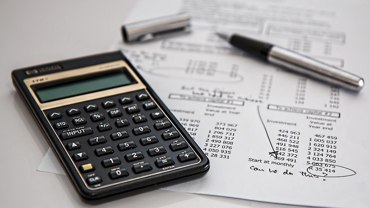 Personne calculant le montant de son indemnité journalière maladie avec une calculatrice et des documents